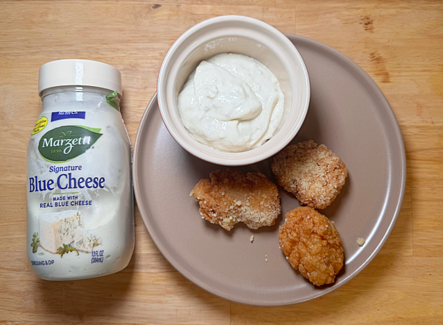 a jar of blue cheese next to boneless parmesan wings and dip 