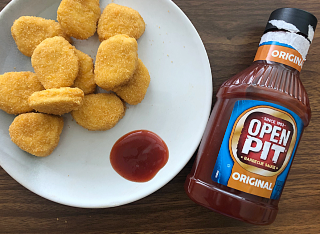 a bottle of open pit bbq sauce next to a plate of chicken nuggets 