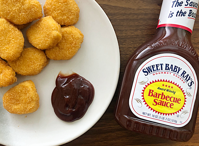 a bottle of sweet baby rays next to a plate of chicken nuggets 