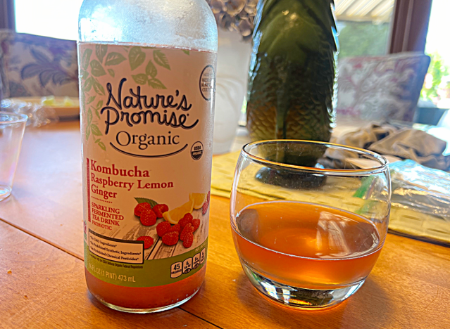natures promise kombucha bottle next to a glass of it 