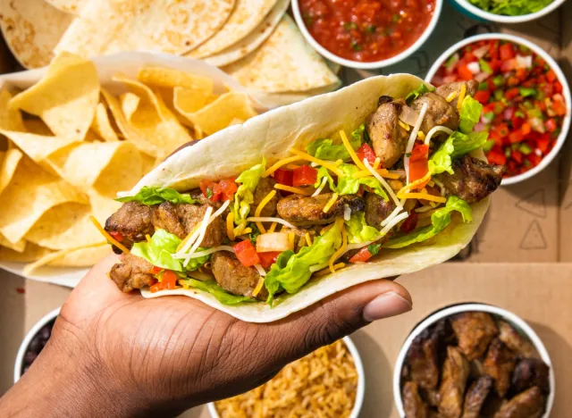 person holding moe's taco from taco meal kit