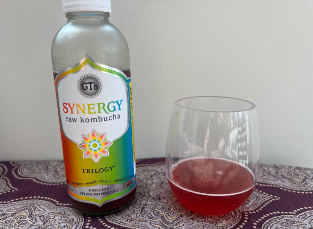 synergy trilogy kombucha bottle next to a glass of it 