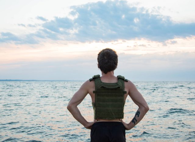 athlete wearing a weighted vest during beach workout looking at the ocean