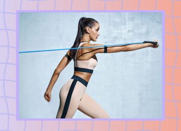 fit woman performing resistance band exercise for her abs in front of grey backdrop
