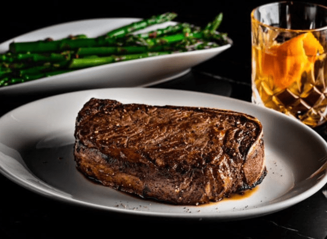 del frisco's prime steak with asparagus and a manhattan