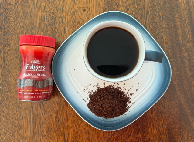 folgers instant coffee can next to a mug of black coffee