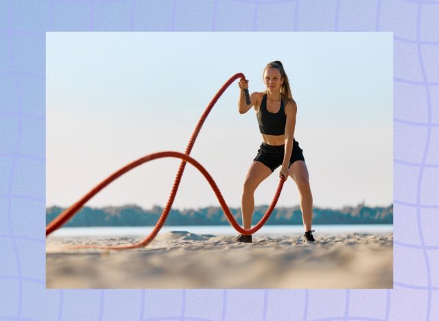 fit woman working out with battle ropes on the beach