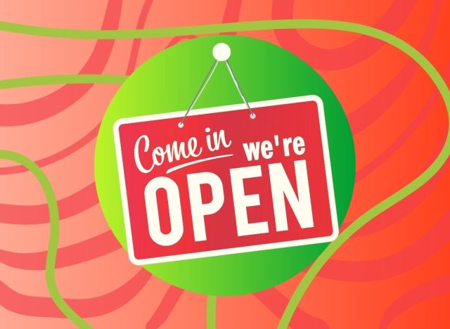 A storefront sign reading, "Come in, we're open," set against a festive holiday background.