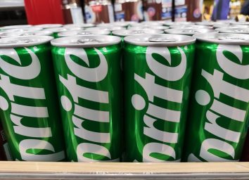 Malang, Indonesia 04-07-2024 : Sprite can in the supermarket. Sprite green can packaging design isolated on supermarket row shelf display background.