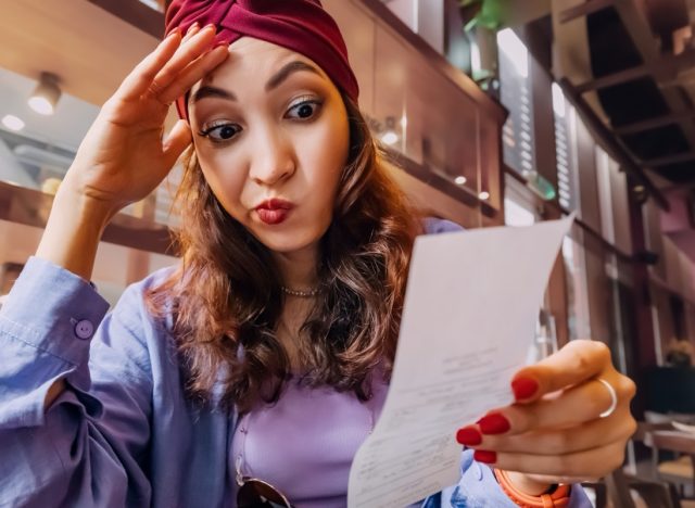 Girl in restaurant had been expecting a reasonable price, but the total seemed much higher. Her mood quickly soured as she realized that her night out had ended up costing more than she had budgeted