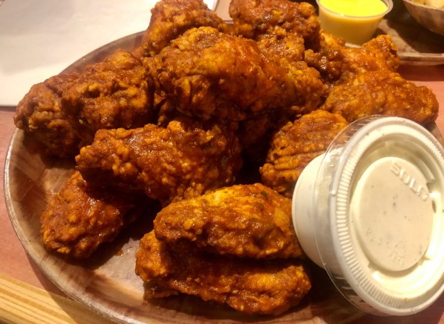 Downers Grove, IL / USA - 7/17/2020 : HOOTERS - Original Style Bone-In Wings with 9-1-1 sauce all over them. Side of Bleu Cheese. Served on a wooden platter.