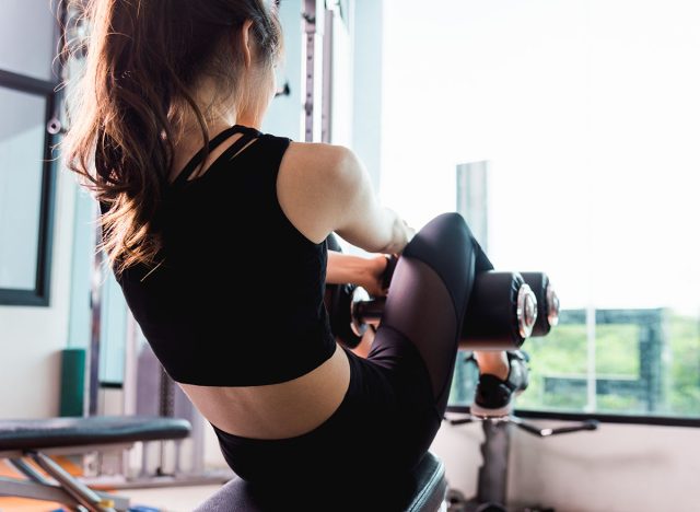 Back young sport beautiful woman training using sit up abs machine she exercise workout at fitness training gym, Healthy bodybuilder lifestyle concept