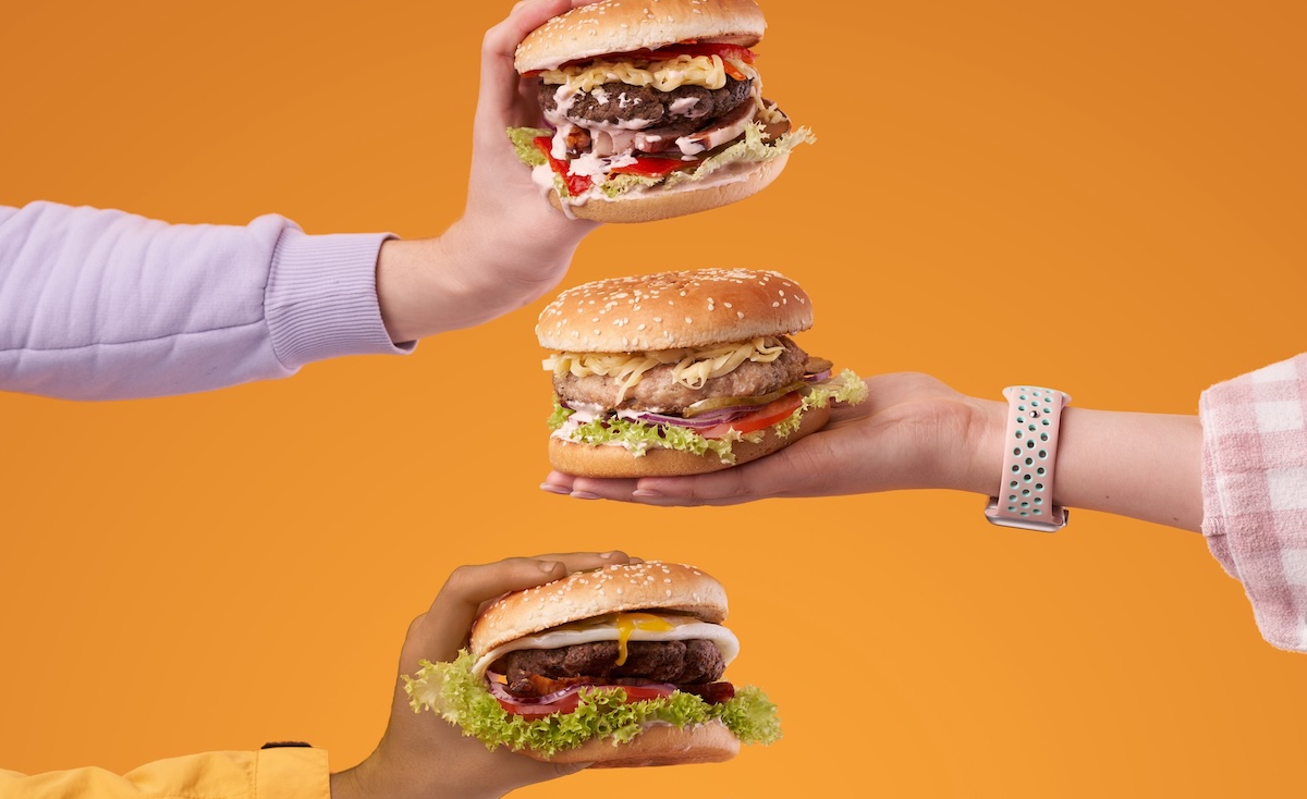 Hands,Holding,Burgers,On,The,Orange,Background.,Burger,With,Juicy