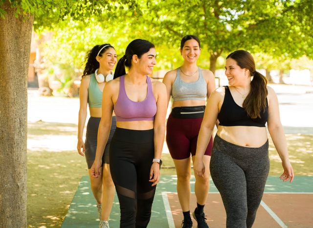 Plus size woman and diverse female friends in activewear walking before running or exercising together outdoors