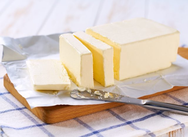 Tasty butter and knife on a kitchen table, selective focus.