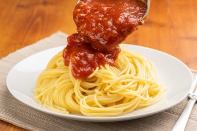 Preparing Meal: Pouring Meat Sauce Over Pasta with Ladle