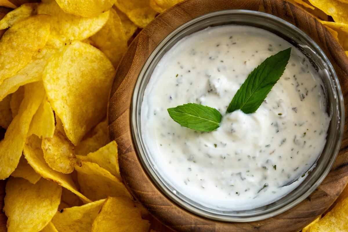 Eating chips with spicy yoghurt on a plate dip yoghurt chips eating chips with sauce