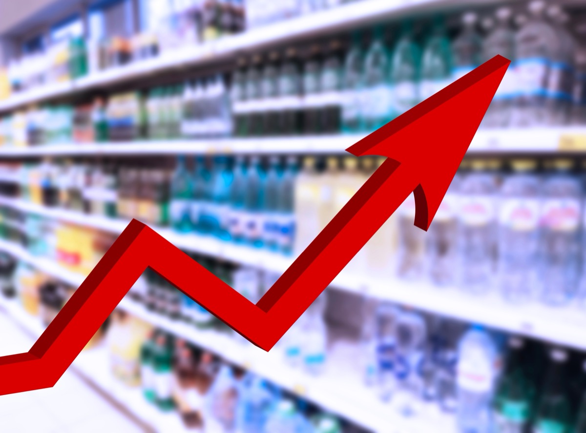 Red growing up big arrow on blur supermarket background. Bar charts and graphs. Rising prices. Inflation concept. Retail industry. Finance and Economy. Stock Market. Store. Tax. Food and Drink. CPG.