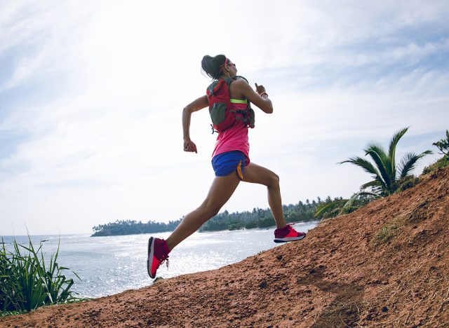 Woman trail runner running on seaside hills, hill sprints 