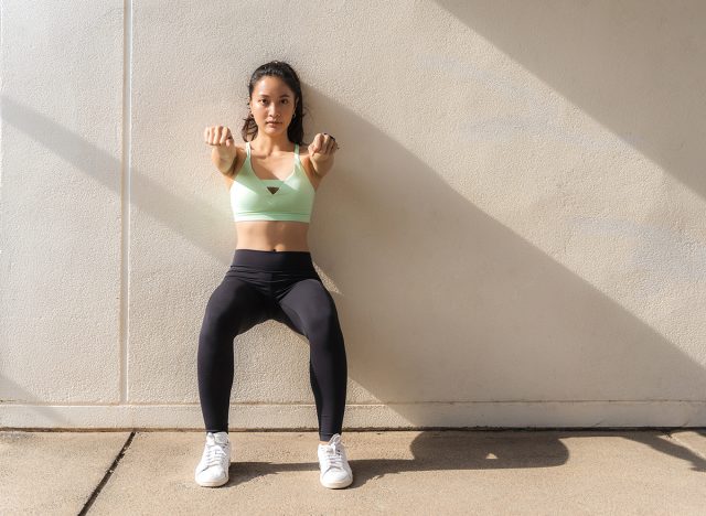 Beautiful Asian women doing "wall sit" exercise.