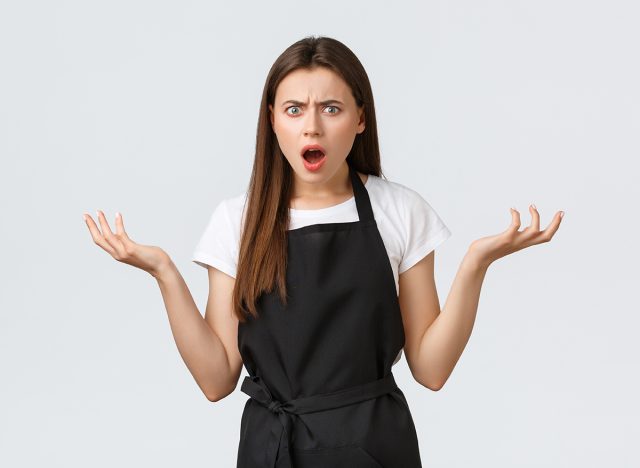 Small business, employees and coffee shop concept. Confused and displeased saleswoman agruing, shrugging shoulders frustrated. Puzzled cafe barista staring bothered, complaining