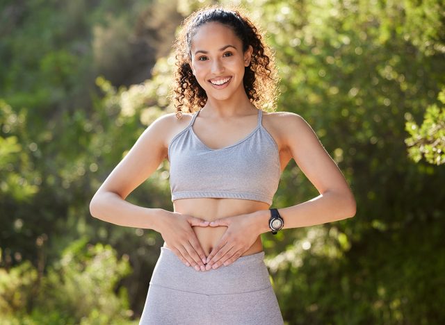 Fitness, heart hands and portrait of runner woman outdoor in park for summer training or workout. Gut health, improvement and wellness with happy sports athlete running in nature for cardio exercise