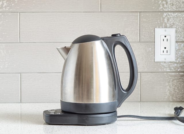 Electric stainless steel kettle on a granite counter top against a ceramic background