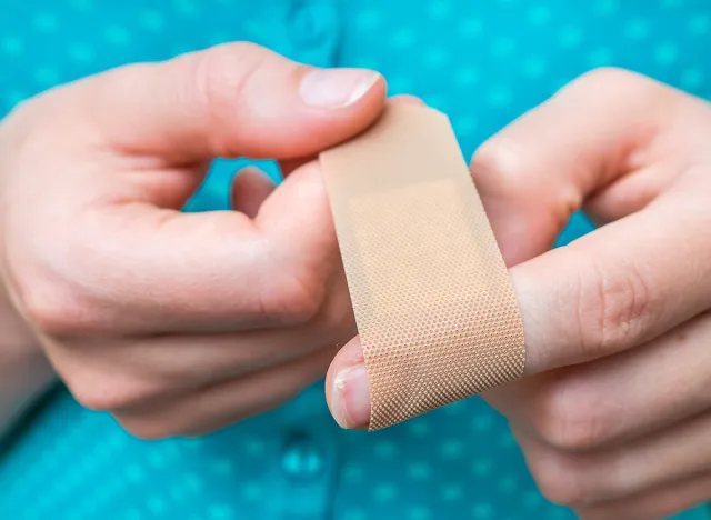 Young woman puts a plaster on her injured finger