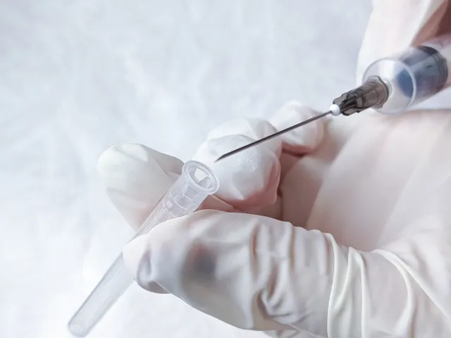 Hands in medical gloves remove cap from syringe needle. Opening syringe. Routine vaccinations for children concept. Vaccination. Sterile medical items. Open syringe needle for injection. Antibiotics.