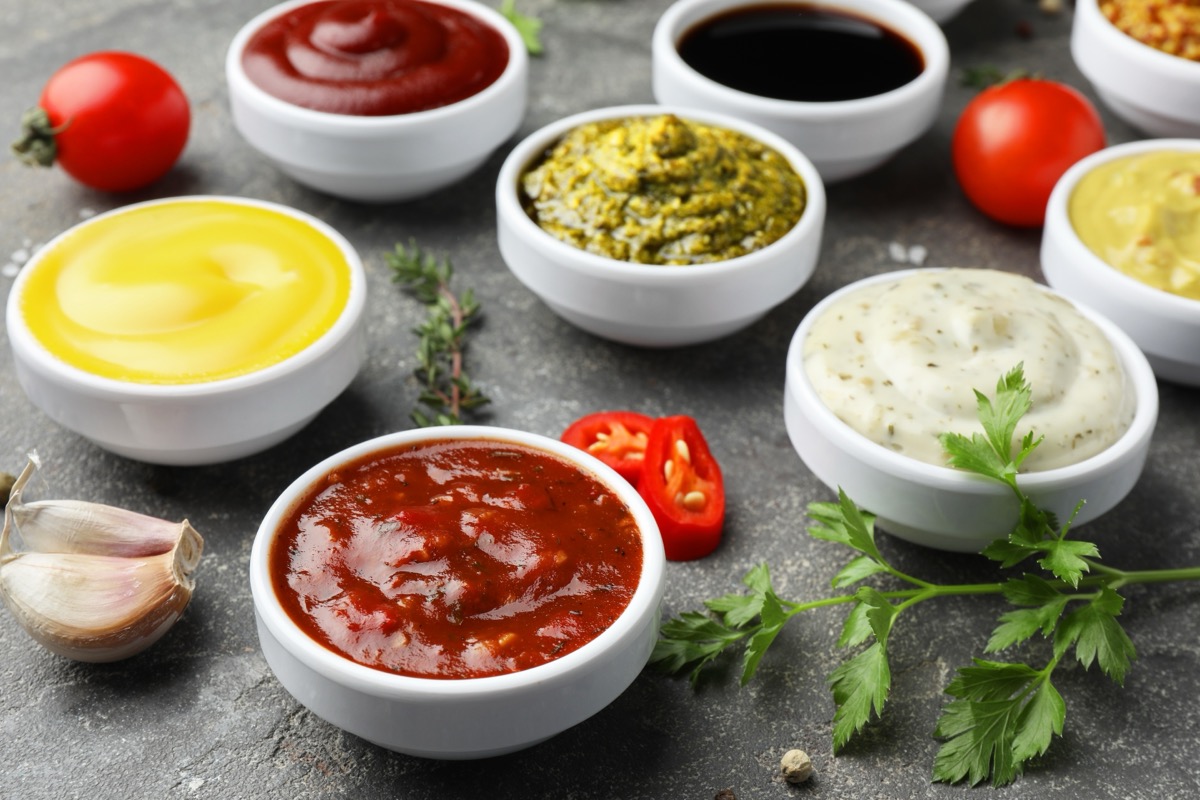 Many different sauces and spices on grey table, closeup