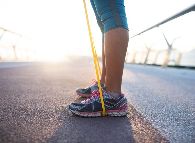 Wearing sneakers. Close up of woman wearing sneakers working out with resistance band