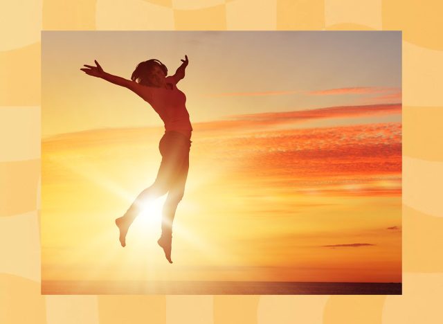 Silhouette of dancer jumping against city in lights of sunrise