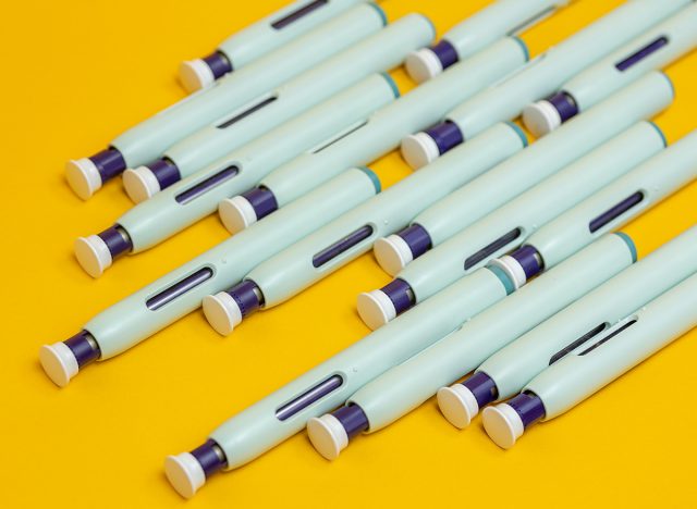 Slanted grouping of self application syringe pens on seamless yellow background. Studio medical equipment still life concept with auto-injector disposable devices.