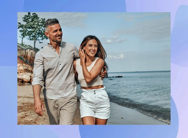 Happy attractive couple walking on beautiful sunny beach. Copy space