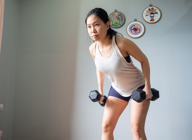 dumbbell row squat position asian woman home workout fitness body weight exercise health training sport healthy lifestyle activity wellness care indoors natural light selective focus