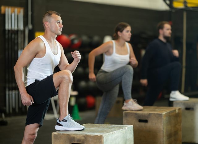 Active young man engaged in box step-up workout during weight training classes