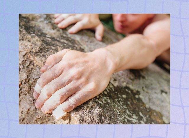 Young man climbing on rock wall, close-up of male hands with tape in magnesium powder.