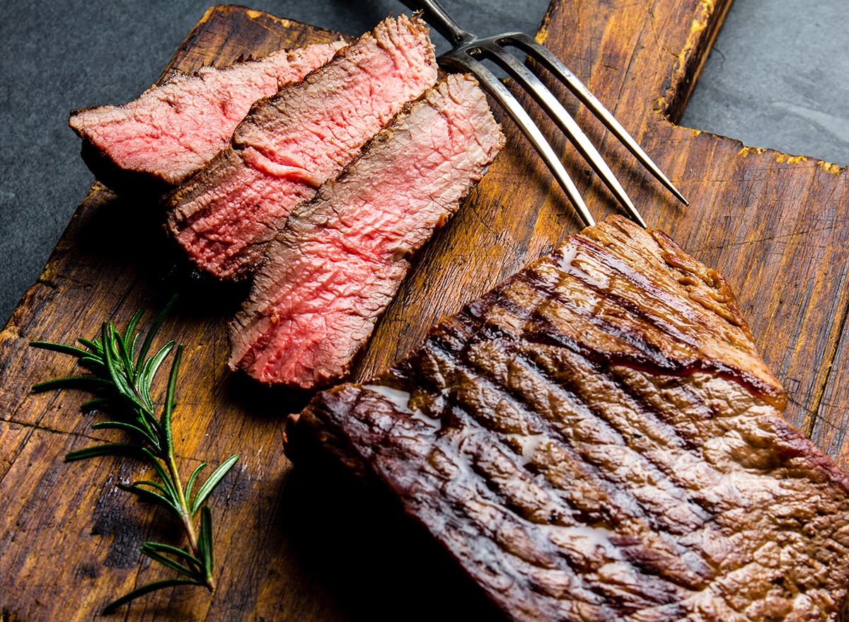 Sliced grilled medium rare beef steak served on wooden board Barbecue, bbq meat beef tenderloin. Top view, slate background.