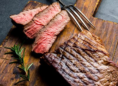 Sliced grilled medium rare beef steak served on wooden board Barbecue, bbq meat beef tenderloin. Top view, slate background.