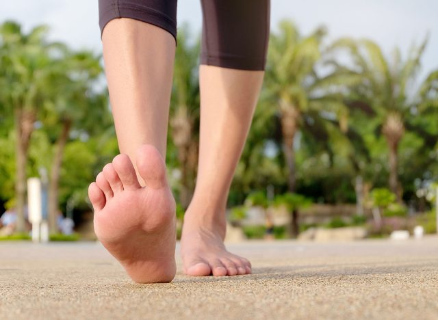 Beautiful woman's feet Walking on a park road Natural background