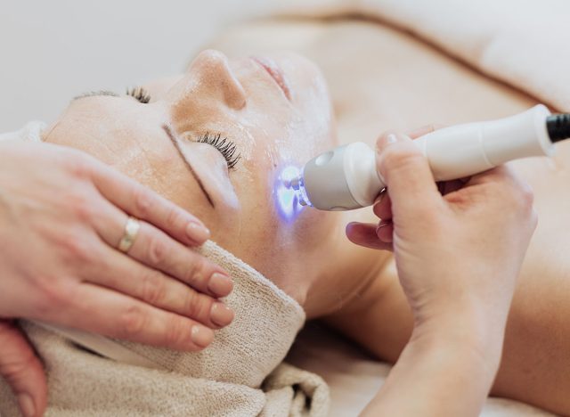 Woman getting laser and ultrasound face treatment in medical spa center