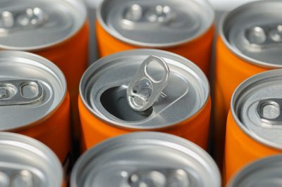 closeup open ring on orange aluminum soda drink' can. Recycling aluminum or metal empty cans from above. Group of cans for reuse and recycle.