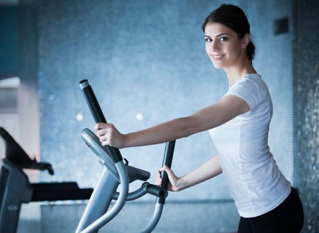 Fitness girl is working out with stepper.Strong brunette with curly hair doing aerobics on stepper.Strong young girl exercising on stepper.Woman doing fitness exercises on stepper at gymnasiumFitness girl is working out with stepper.Strong brunette with curly hair doing aerobics on stepper.Strong young girl exercising on stepper.Woman doing fitness exercises on stepper at gymnasium