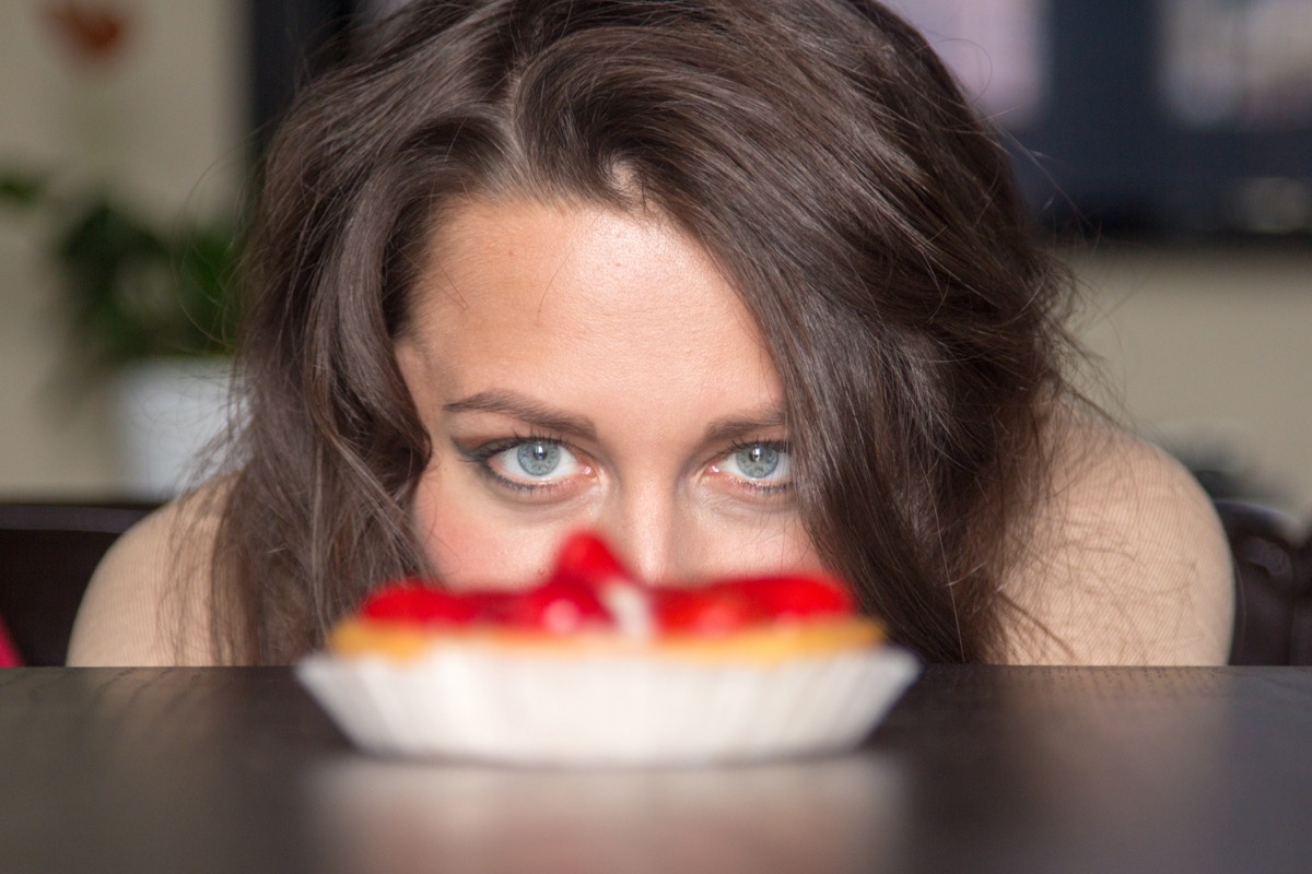 Pretty girl Looking to strawberry cake in living room