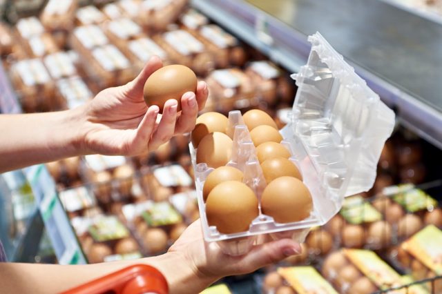 Hands of woman with packing eggs in supermarket