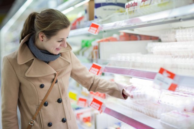 pretty young woman buying groceries in a supermarket/mall/grocery store (color toned image; shallow DOF)