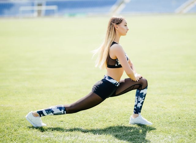 Fitness woman doing lunges exercises for leg muscle workout training, outdoors. Active girl doing front forward one leg step lunge exercise