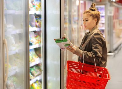 Woman choosing frozen food from a supermarket freezer