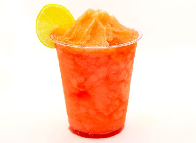 Strawberry slush with lemon slice served in a disposable cup.
