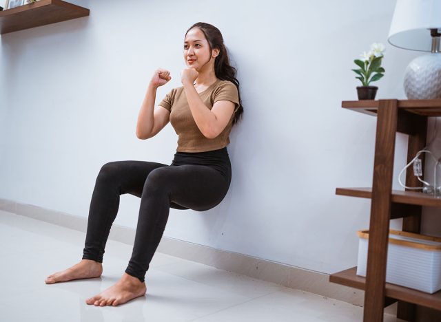 portrait of young asian woman squating against the wall at home